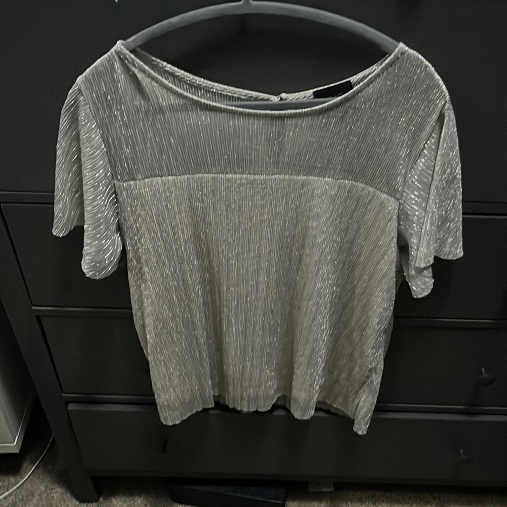 Flowy top with a tan base and silver overlay. Flounced sleeves .
